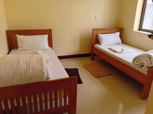 two beds in a small room with towels on them at Kilimanjaro Budget in Moshi