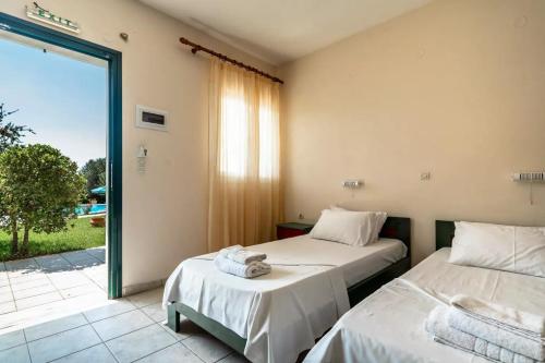 two beds in a room with a sliding glass door at Anemona studio A in Kefallonia