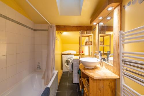 a bathroom with a tub and a sink and a washing machine at Appartement style loft Chamonix in Les Houches