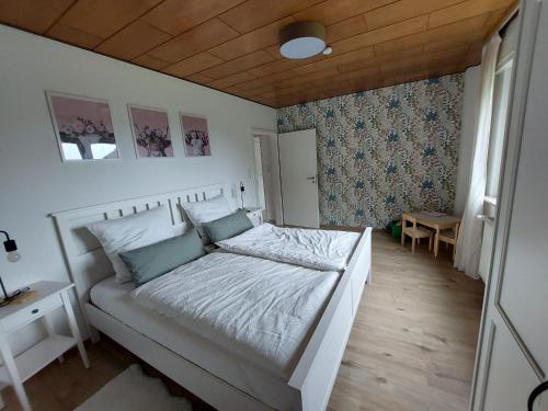 a bedroom with a white bed with a wooden ceiling at Ferienhaus Dorfidylle in Oberzent