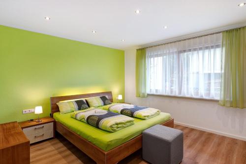 a green bedroom with a bed and a window at Ferienwohnung Käshammer in Kappelrodeck