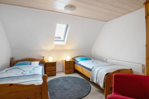 two beds in a room with a red chair at Ferienwohnung Horstmann in Meldorf