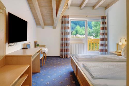 a hotel room with two beds and a television at Hotel Residence Olympia Sarntal in Sarntal