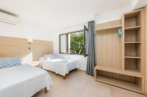 a bedroom with a bed and a desk and a window at Apartamento Aquamarina 7 in Cala Ferrera