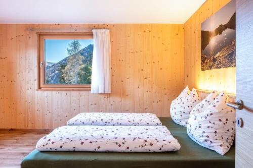 a bedroom with two beds and a window at Mittnackerhof Apartment Kamille in Sarntal