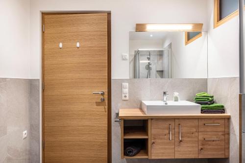 a bathroom with a sink and a wooden door at Mittnackerhof Apartment Kamille in Sarntal