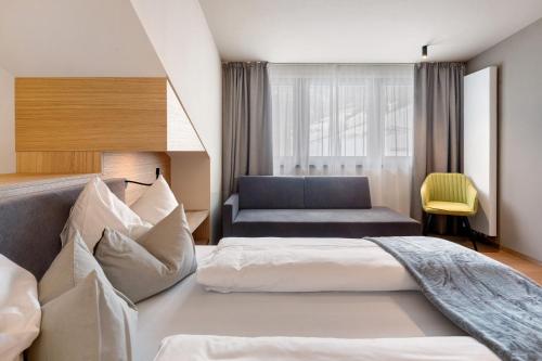 ein Hotelzimmer mit einem Bett und einer Couch in der Unterkunft Hotel Murrer relaxe.nature.gusto in Sarntal