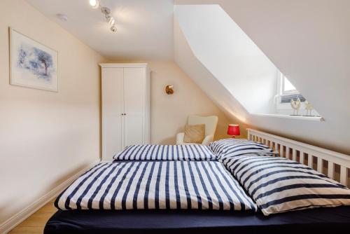 a bedroom with a bed with striped sheets in a attic at Sabines Ferienwohnung in Glückstadt
