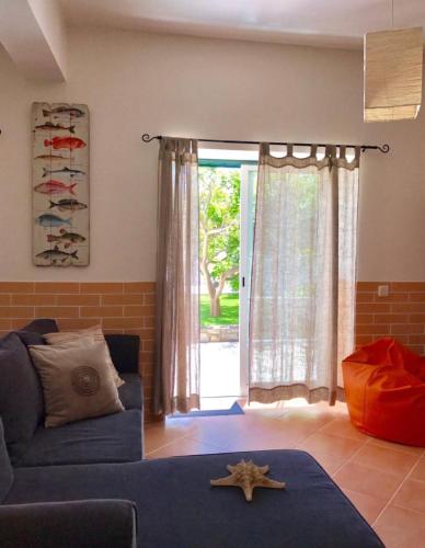a living room with a blue couch and a window at Casa Sagres in Vila do Bispo