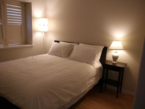 a bedroom with a white bed with two lamps at Marpole Guest House in Vancouver