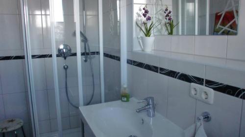 a white bathroom with a shower and a sink at Ferienwohnung Stella Fiante in Juliusruh