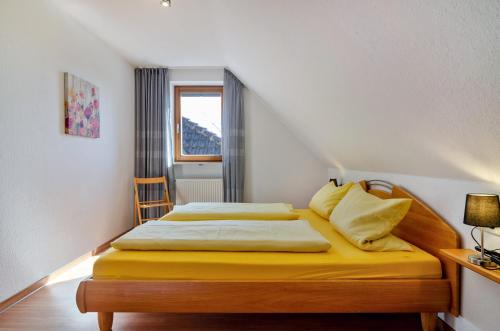 a bedroom with a bed with yellow sheets and a window at Ferienwohnung Keller in Hagnau