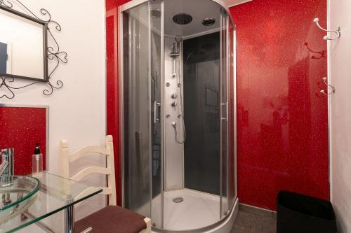 a glass shower in a bathroom with red walls at L'abreuvoir du Leffo in Allineuc