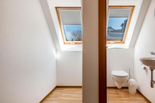 a bathroom with a toilet and two windows at Ferienwohnung Keller in Hagnau