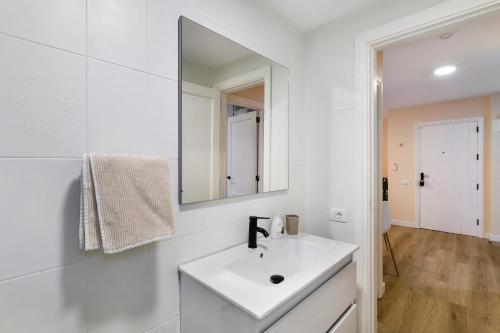 a white bathroom with a sink and a mirror at Apartamento Con Piscina Arinaga in Arinaga