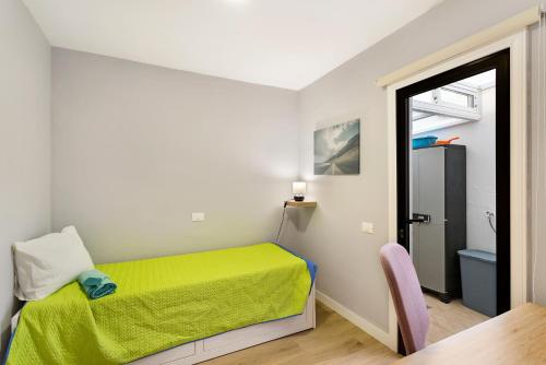 a small bedroom with a green bed and a chair at Apartamento Con Piscina Arinaga in Arinaga