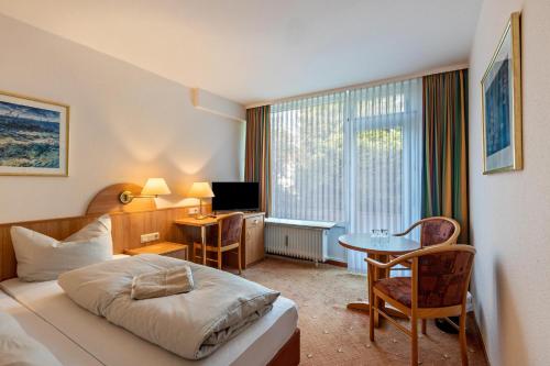 a hotel room with a bed and a desk and a table at Aparthotel am Stadtpark in Bad Sachsa