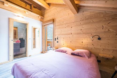 a bedroom with a bed in a wooden wall at Chalet - Le crey rond in Valloire