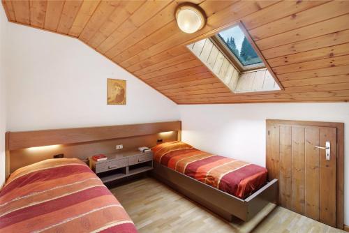 a attic bedroom with two beds and a skylight at Mansarda Maema in Moena