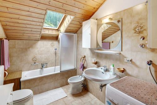a bathroom with a sink and a toilet and a tub at Mansarda Maema in Moena