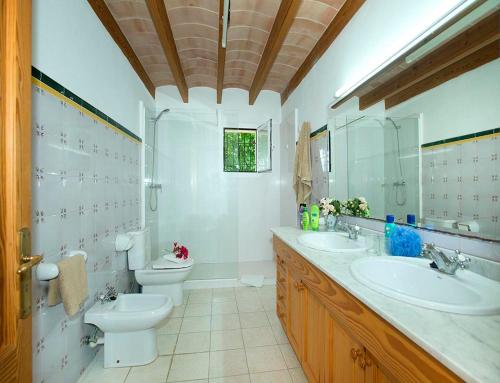 a bathroom with two sinks and a toilet and a mirror at Villa Tancotes in Pollença