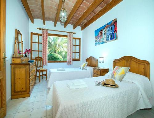 a bedroom with two beds and a dresser and a window at Villa Tancotes in Pollença