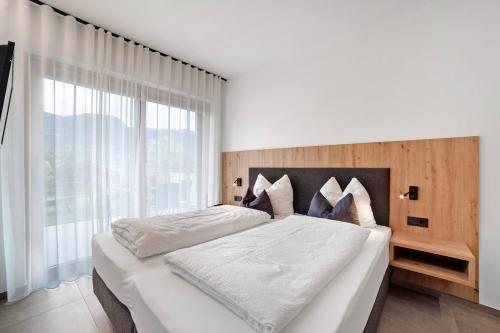 a bedroom with a white bed with a large window at Haus Nummer 9 in Marlengo