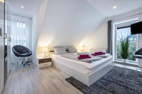 a white bedroom with a bed and a large window at To Huus am Steinhuder Meer in Steinhude