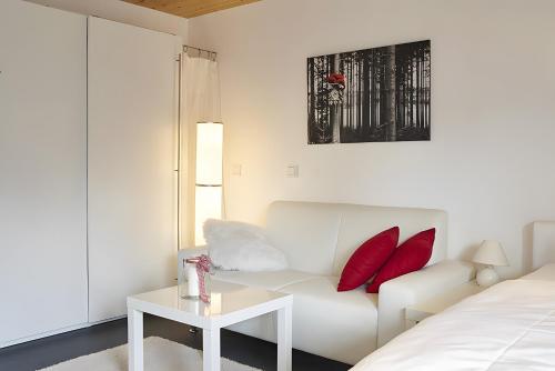 a white living room with a white couch and red pillows at Charmingsuite in Bad Teinach-Zavelstein