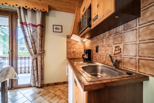 a kitchen with a stainless steel sink and a window at La Flèche d'Or in Châtel