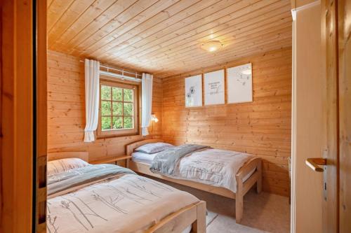 zwei Betten in einer Blockhütte mit Fenster in der Unterkunft Moi Holzhaisel in Elmstein