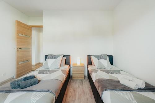 two beds in a room with wooden floors at Maison avec jardin proche Dinan in Trévron