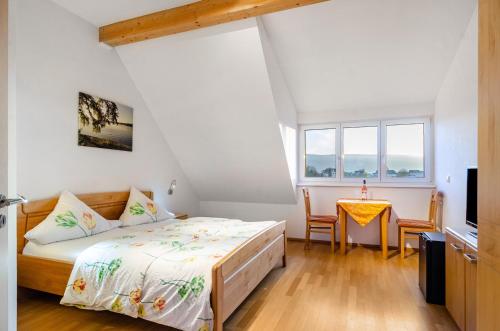 a bedroom with a bed and a table and windows at Pension Zum Talhof in Reichenau