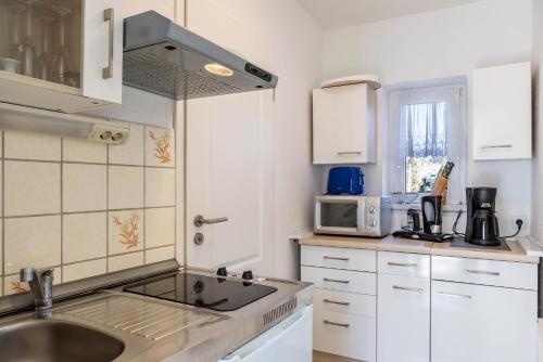 a white kitchen with a sink and a microwave at Ferienwohnung bei Will in Stützerbach