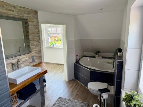 a bathroom with a tub and a sink and a toilet at Ferienhaus Neeborg in Zetel