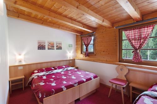 a bedroom with a bed and a chair in a cabin at Appartamenti Camilla in Canazei