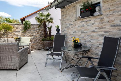 a patio with chairs and a table and a brick wall at Ferienwohnungen Eulenspiegel in Breisach am Rhein