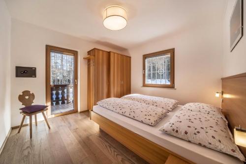 a bedroom with a bed and a chair and a window at Ferienwohnung Hirzer Edelweiss in Avelengo