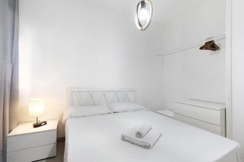 a white bedroom with a white bed with two towels on it at La Pelusa Peschiera in Peschiera del Garda