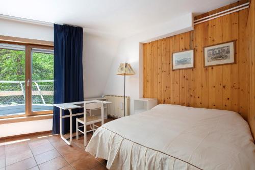 a bedroom with a bed and a desk and a window at Appartamenti Larice Pila in Pila