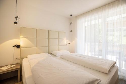 a bedroom with a bed with white sheets and a window at Apartment Treï Residence Bun Ste in San Vigilio Di Marebbe
