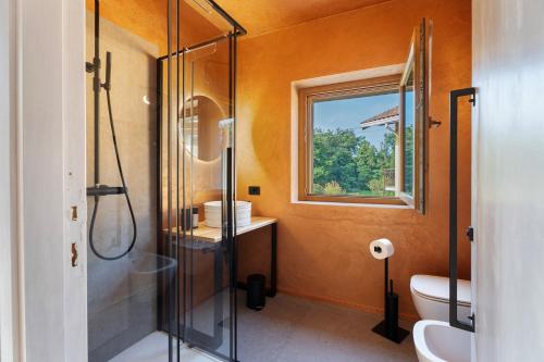 a bathroom with a shower and a toilet and a window at Decanter House in Borgomanero