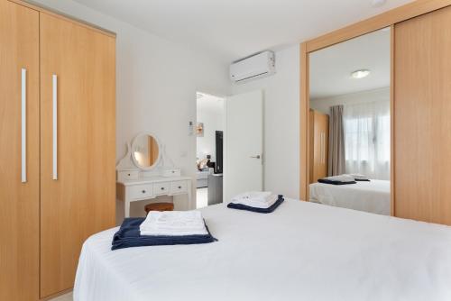 a bedroom with a large white bed and a mirror at La Casita Encantada in Corralejo