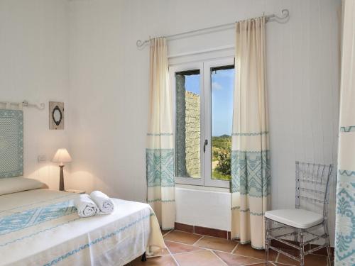 a bedroom with a bed and a window and a chair at Li Conchi 44 in Castiadas