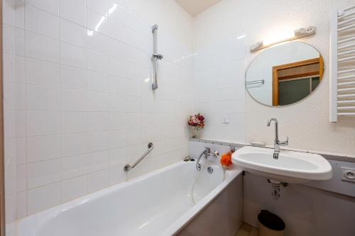 a bathroom with a sink and a tub and a mirror at Les arolles in Valloire