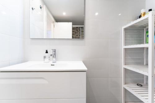a white bathroom with a sink and shelves at Paraiso in Fuengirola