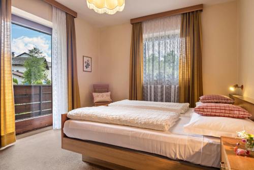 a bedroom with two beds and a large window at Ferienwohnung 4 Vikoler in Vols am Schlern