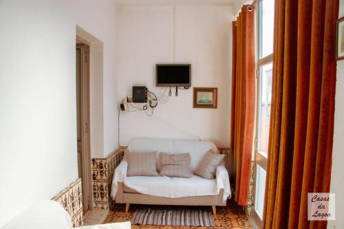 a living room with a white couch and a tv at Encanto da Praia in Santo André