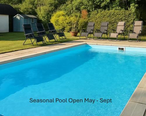 a swimming pool with chairs in a yard at April Cottage in Hordle