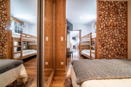 a bedroom with two beds and a wall of logs at Au Rêve Savoyard 3 - 6 personnes in Morillon